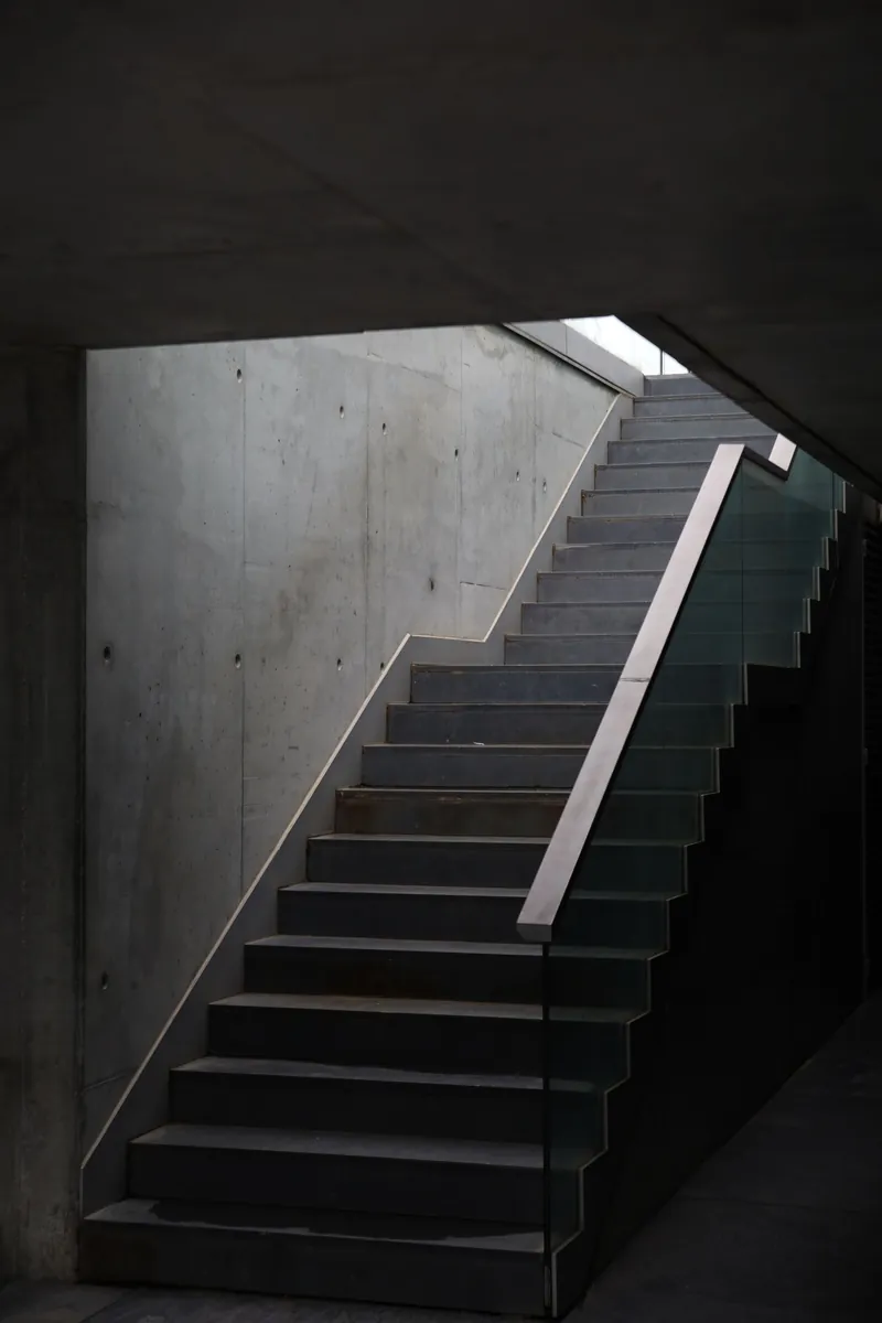 Escalera de concreto en penumbra con la luz entrando desde arriba